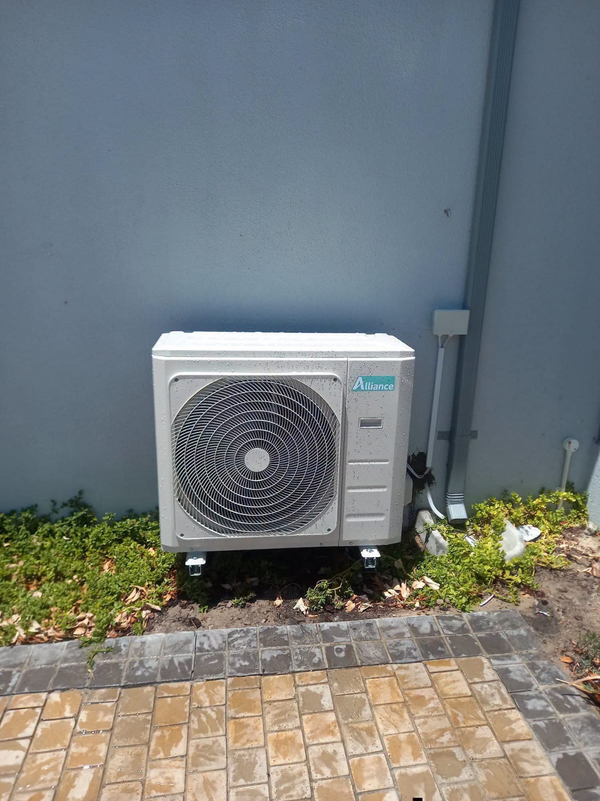 Outdoor Alliance air conditioning condenser unit mounted against an exterior wall